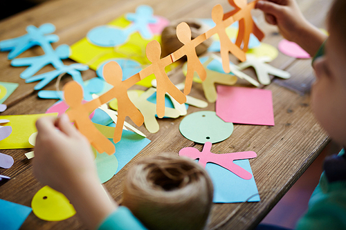 Close-up of little boy holding paper people figures