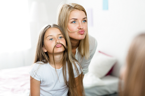 Funny girl and woman imitating moustaches from their long hair