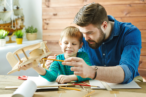 Father explaining his son structure of detail of wooden airplane