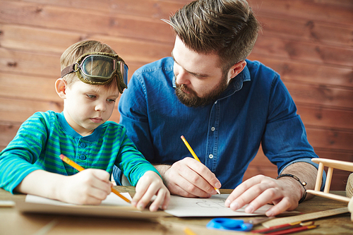 Young man and his son drawing sketch