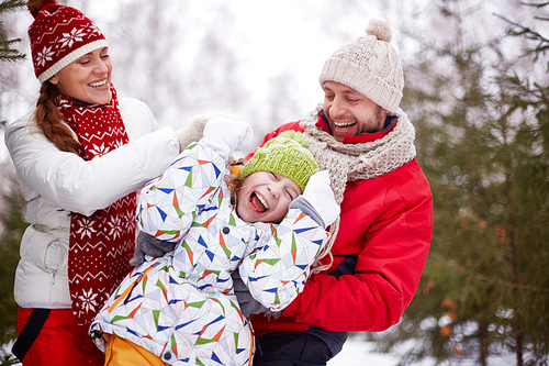 Happy parents playing with carefree daughter in park