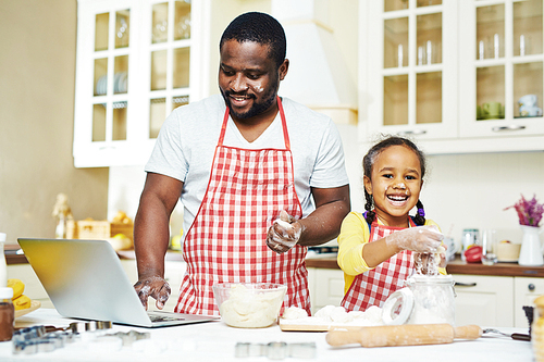 Cute daughter with dough and her father cooking pastry together