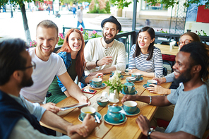 Circle of happy friends having nice time in cafe