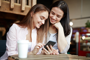 Two groupmates reading sms in smartphone while sitting in cafe