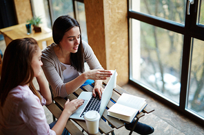 Two girls carrying out electronic assignment or discussing project