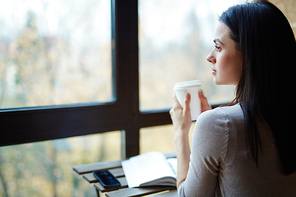 Pretty student with hot coffee relaxing in cafe