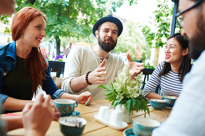 Group of friends communicating at cafe and drinking tea