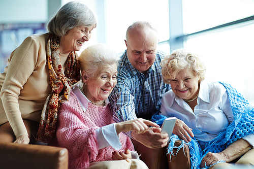 Group of senior friends watching photos on mobile phone