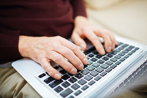 Close-up of senior man typing on laptop