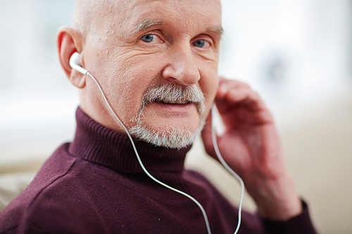 Portrait of positive mature man listening to music