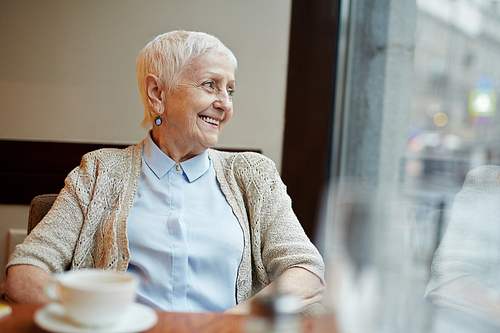 Happy retired female relaxing in cafe