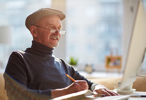 Smiling old man working with computer