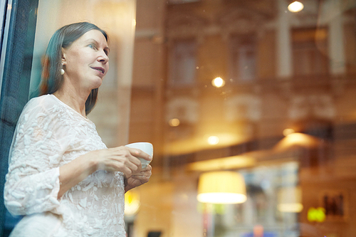 Restful female with cup of tea looking through cafe window