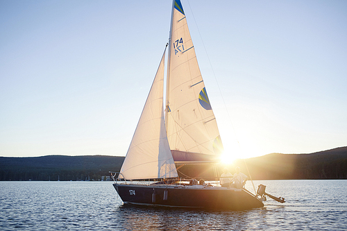 Sailboat with two seniors floating on river at dawn