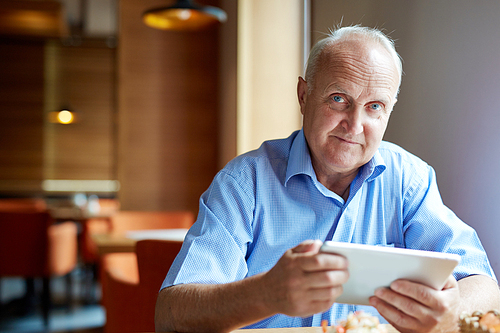 Portrait of senior man using touchpad at cafe