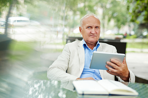 Senior businessman using tablet pc at cafe