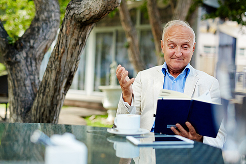 Senior man drinking his coffee and reading his notes