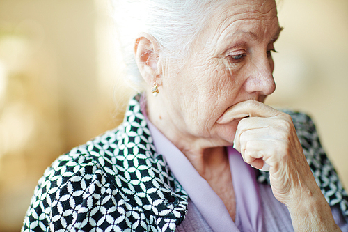 Pensive senior woman with her hand by mouth
