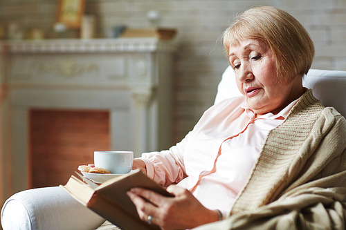 Senior female reading book in armchair