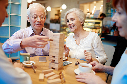 Senior people constructing tower from wooden blocks