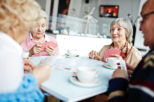 Group of friendly seniors playing cards at leisure