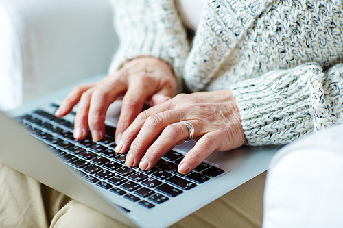 Senior female typing on laptop keypad