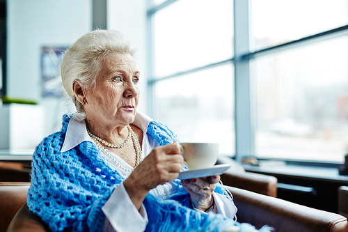 Pensive senior female having tea