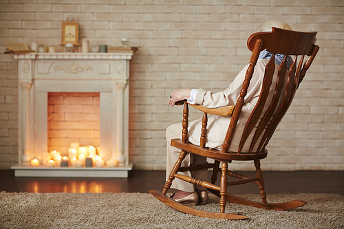 Woman in rocking-chair sitting in front of fireplace at home