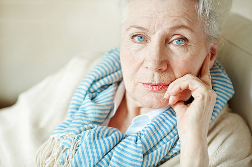 Serious mature woman touching her face while 