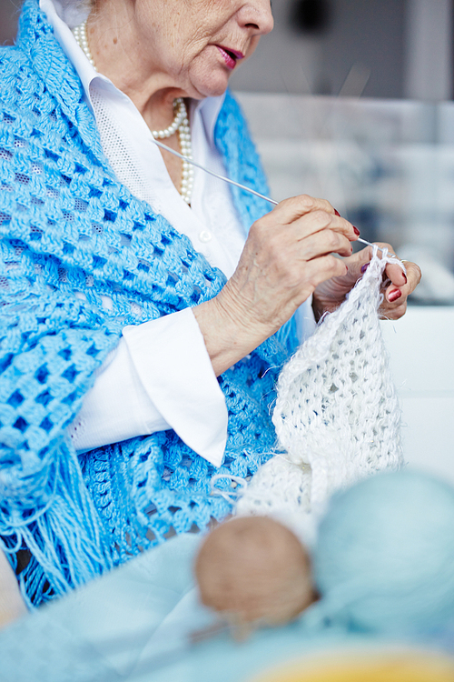Elderly woman knitting woolen clothes at leisure