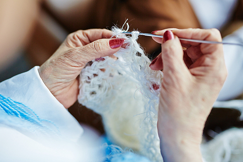 Human hands during knitting woolen clothes