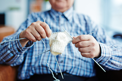 Elderly man knitting woolen sock at leisure