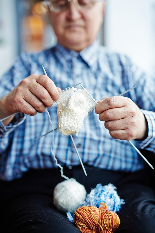 Elderly man knitting woolen socks