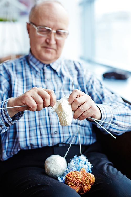 Senior man knitting a woolen sock