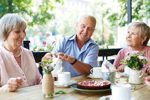 Group of senior friends having tea with cake in cafe