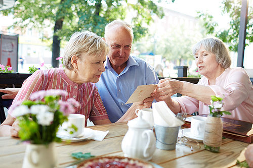 Senior woman showing her photo to one of friends during hang-out