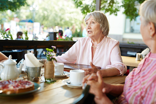 Grey-haired female telling something to her friends