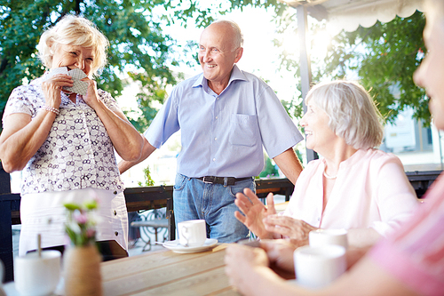 Several senior people sitting in outdoor cafe and talking