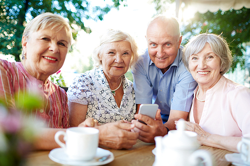 Grey-haired senior females and man sitting in outdoor cafe