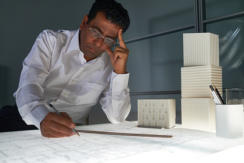 Pensive engineer looking at sketch of architectural project