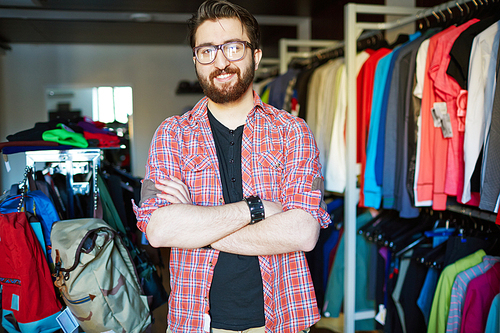 Portrait of young handsome salesman standing in clothing store