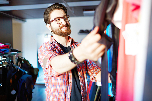 Handsome young man shopping for clothes at shop