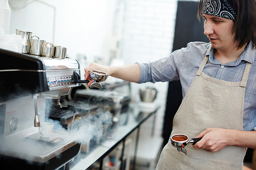 Professional barista preparing black coffee in cafeteria