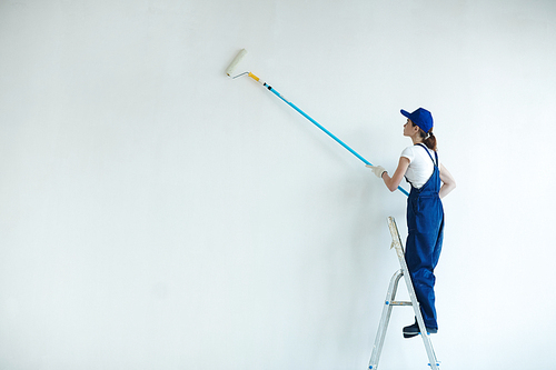 Woman with paintroller painting wall of her room