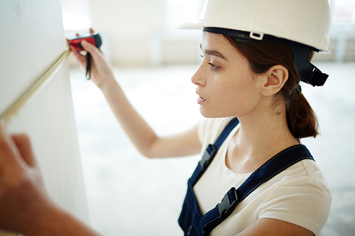 Woman in harhat measuring width of wall