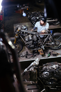 Young man repairing motor of custom bike