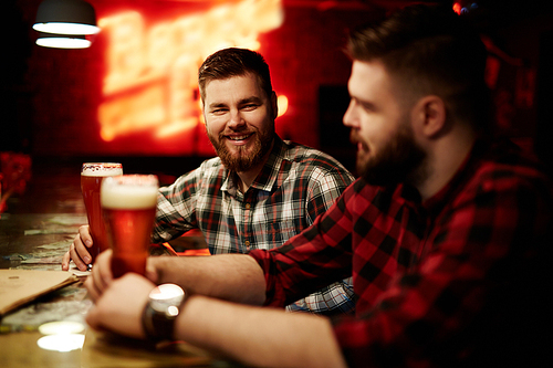 Two friends talking in bar by glass of beer