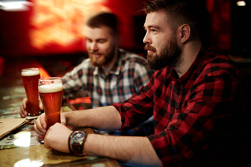 Man drinking beer with his friend at the bar