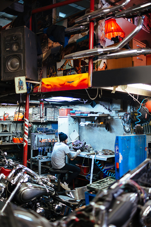 Man repairing carburetor of motorcycle in garage or workshop