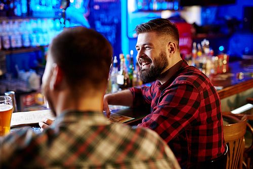 Happy bearded man and his friend sitting in pub